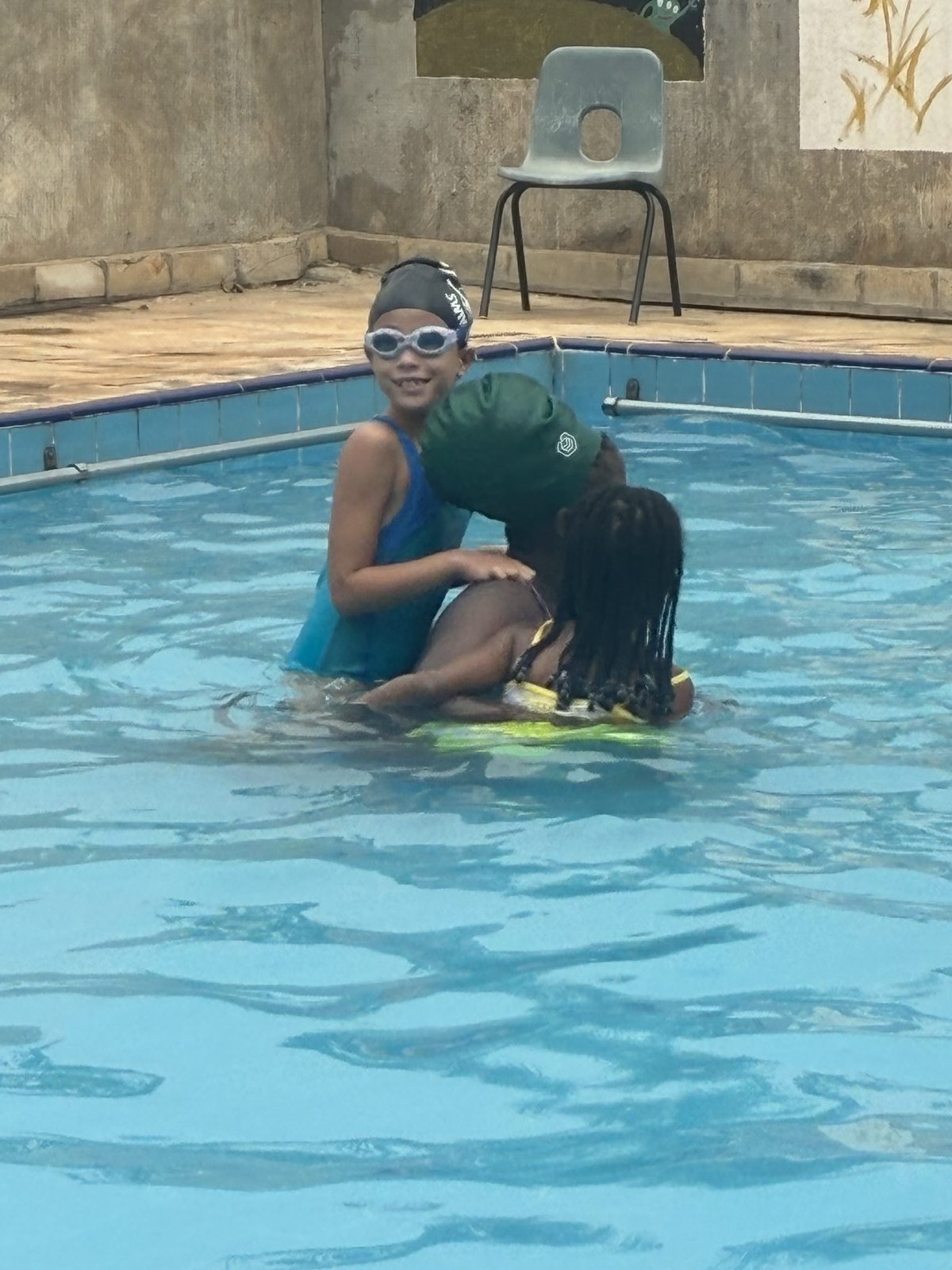 An older swimmer helps our youngest learner